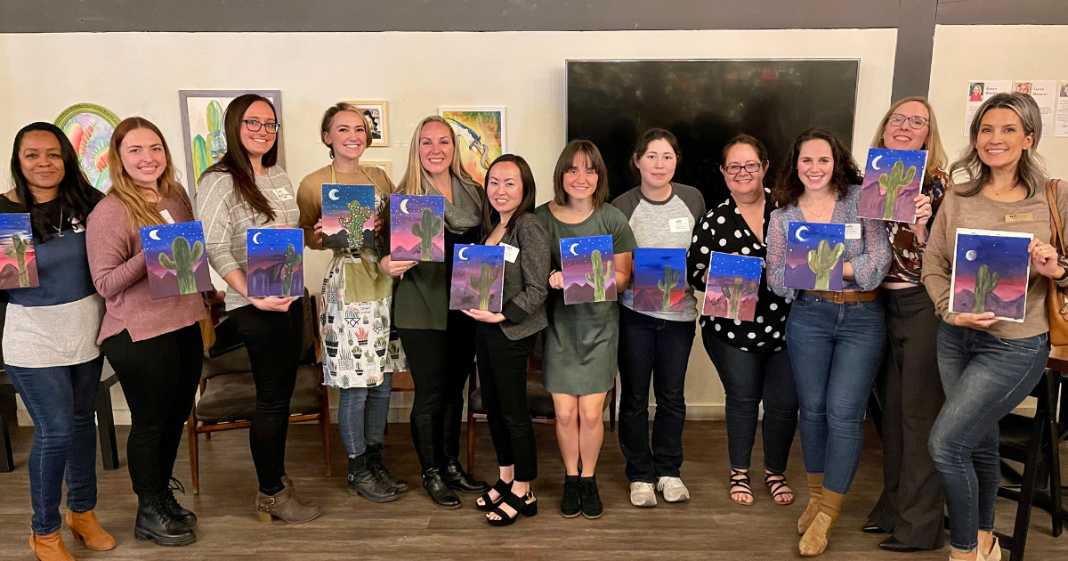 Mentorship Program Participants painted wall hangings and posed together in a line to show their artwork